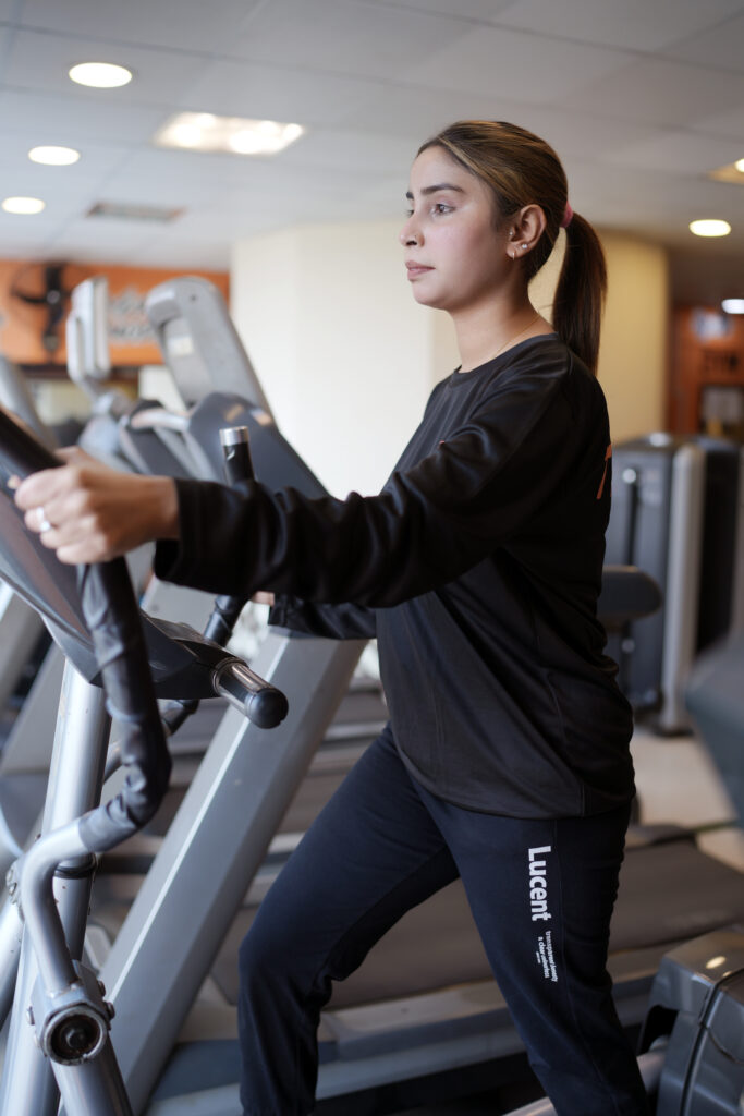 Woman working out on an elliptical at Curve Fitness Pro, wearing black activewear in a modern gym.